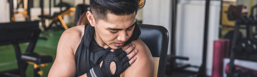 Man working out in the gym but stopped due to shoulder pain, and is rubbing his shoulder Man working out in the gym but stopped due to shoulder pain, and is rubbing his shoulder